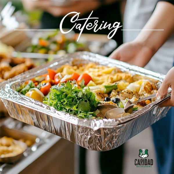 Hands holding a large foil catering tray filled with Caridad Restaurant's Spanish food.
