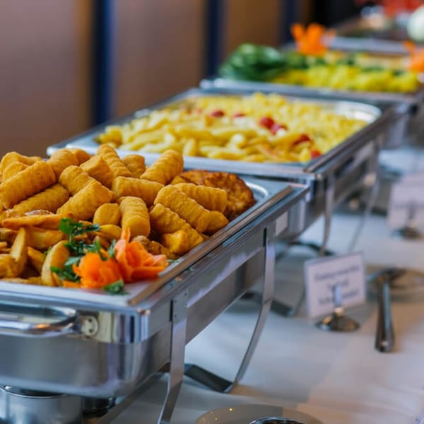 Chafing dishes filled with golden fried croquettes, potato wedges, and other Spanish dishes.